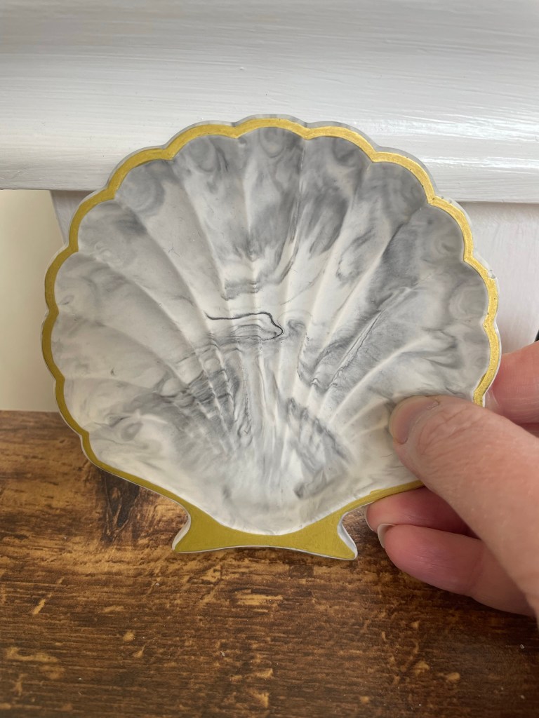 a marble shell trinket dish, with a gold painted rim.